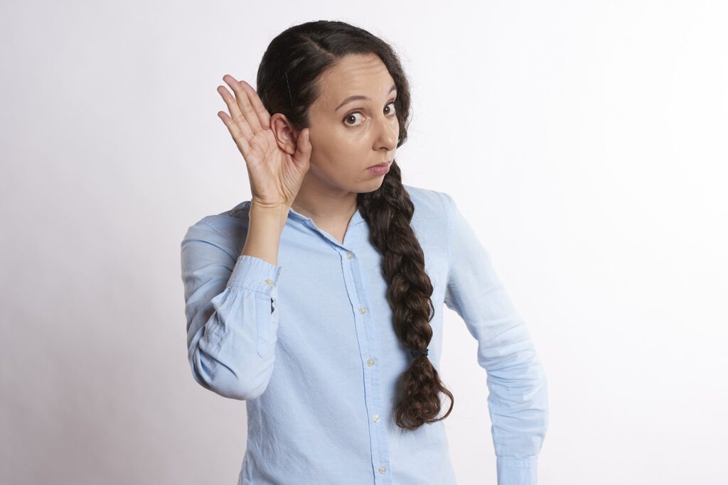 A lady shown cupping her ear to listen to sounds, as though she is learning auditory discrimination - an important skill in self-monitoring for articulation students.