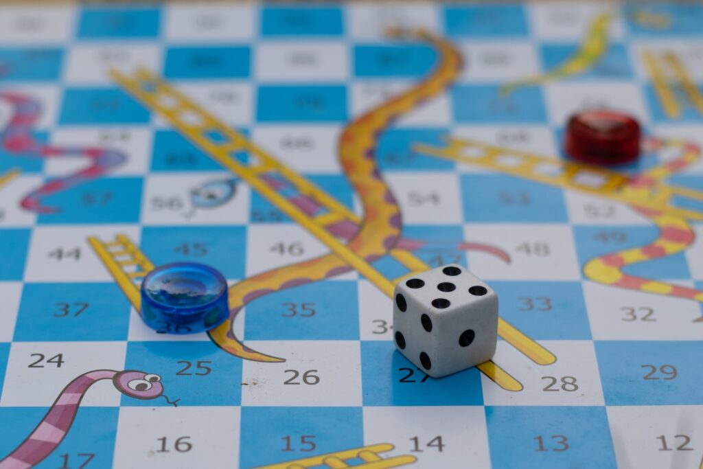 A close up of a board game depicting snakes and ladders with dice.