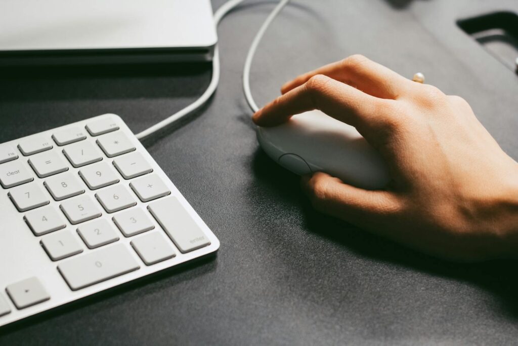 Person Holding Computer Mouse. A computer mouse provides more precision when navigating your computer monitor. This may be important for both the clinician and client when providing speech teletherapy. 